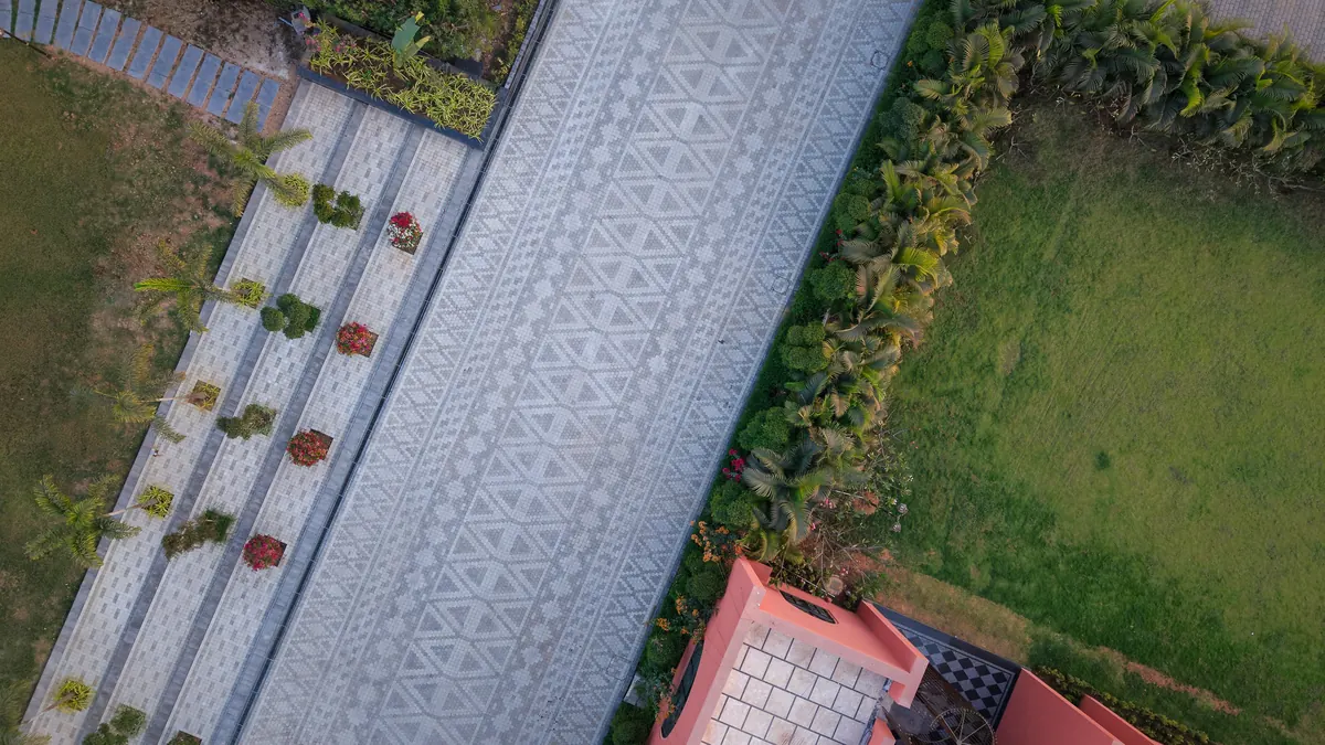 Geometric concrete paver laying pattern across a landscaped walkway, aerial view